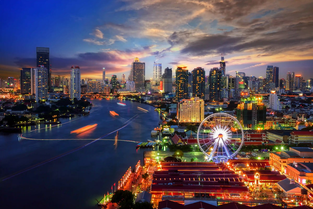 Beleuchtete Skyline von Bangkok bei Nacht mit Fluss, Hochhäusern und Riesenrad