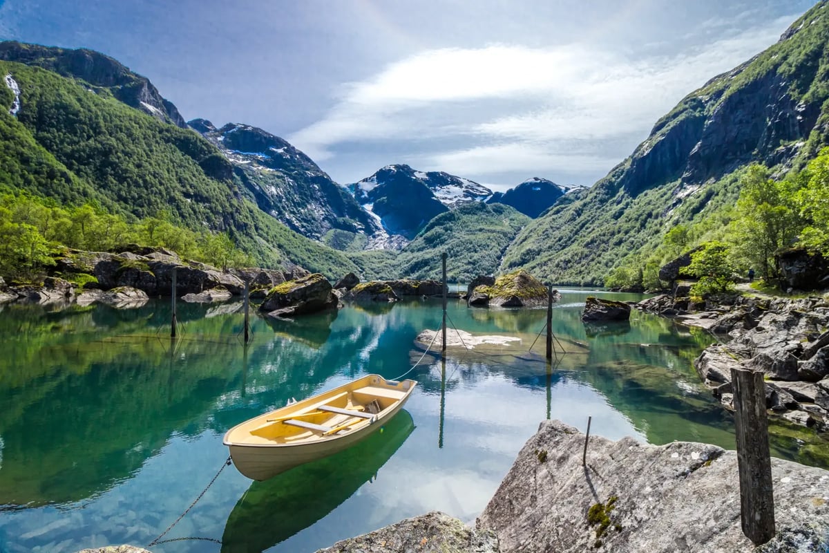 Ruderboot auf einem Bergsee vor dem Bondhus-Gletscher und den umliegenden Bergen.