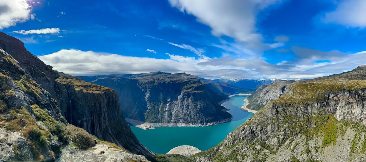Panoramablick über einen norwegischen Fjord mit steilen Felswänden und türkisfarbenem Wasser.