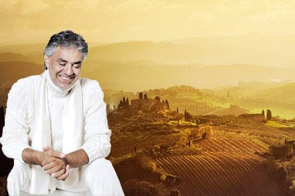 Andrea Bocelli in heller Kleidung sitzt entspannt vor sanften Hügeln und Weinlandschaft in warmem Abendlicht