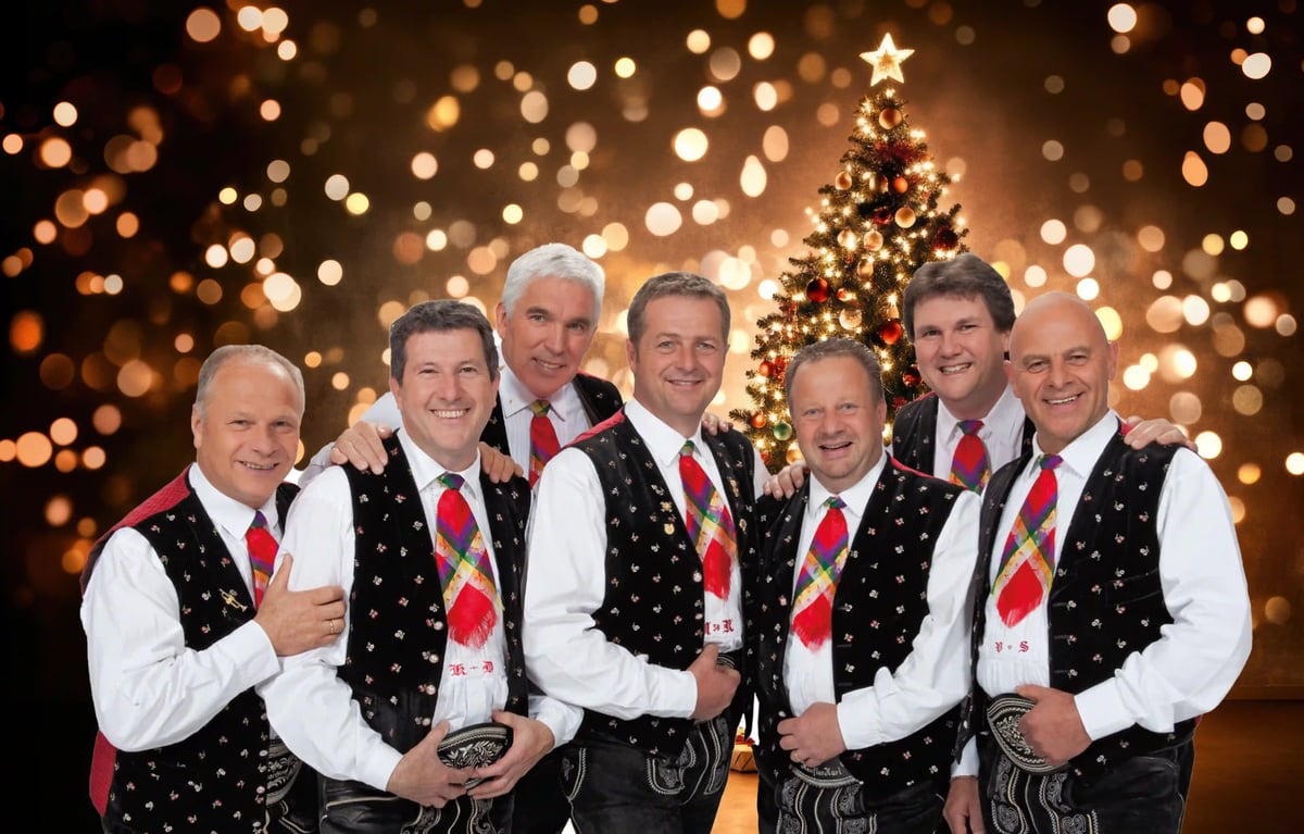 Die Kastelruther Spatzen in traditioneller Tracht vor geschmücktem Weihnachtsbaum.