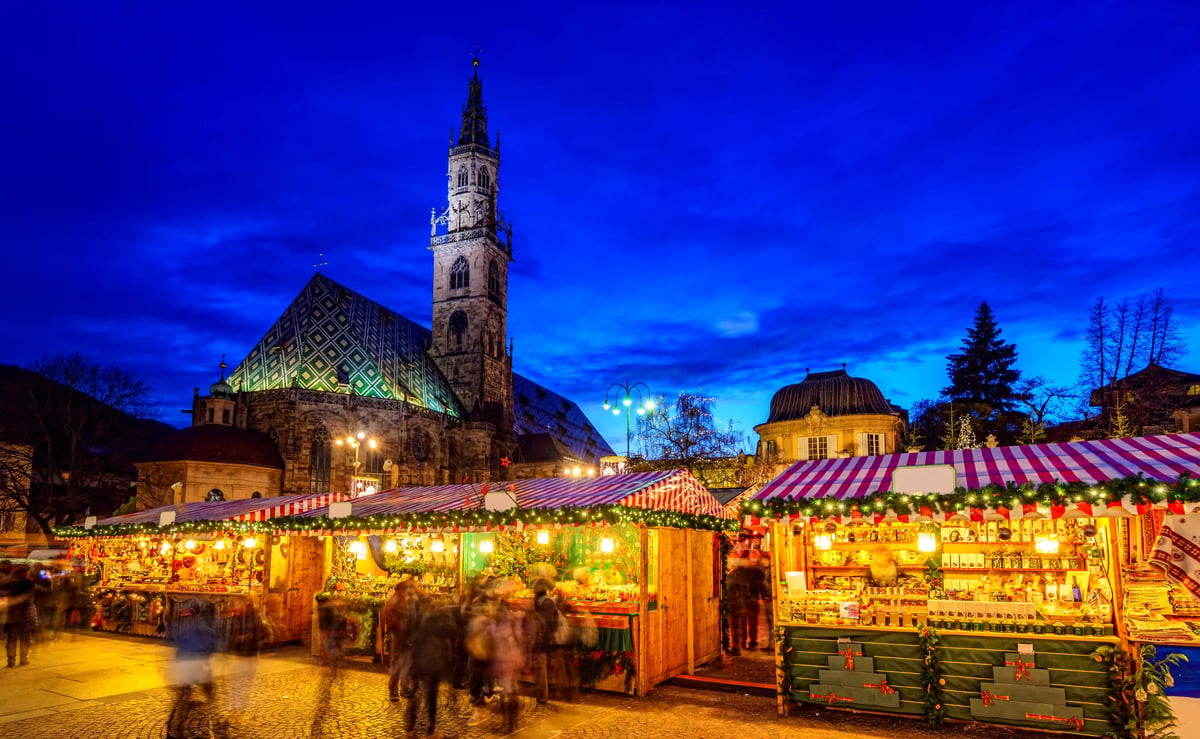Weihnachtsmarkt auf dem Waltherplatz in Bozen mit Marktständen und Dom im Hintergrund.
