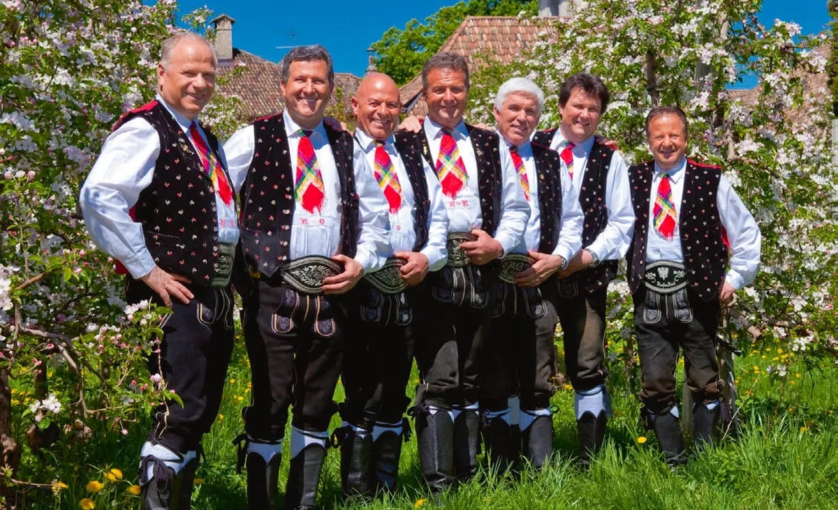 Musikgruppe Kastelruther Spatzen in traditioneller Tracht vor blühenden Bäumen