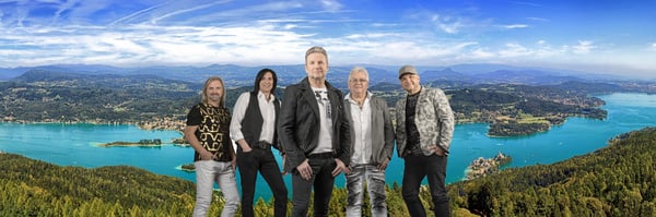 Fünf Musiker stehen vor dem Wörthersee