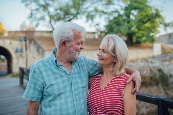Lächelndes älteres Paar spaziert entspannt Arm in Arm durch eine historische Umgebung