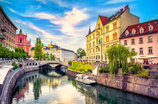 Altstadt von Ljubljana mit bunten Fassaden Brücke und Booten entlang des Flusses