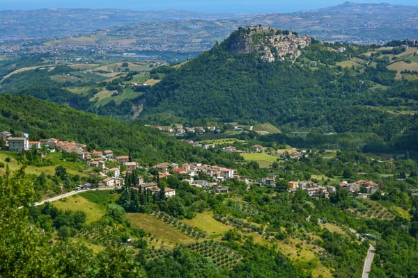 Mittelalterliches Bergdorf Civitella del Tronto mit dicht stehenden Häusern, grünen Hügeln und blauem Himmel