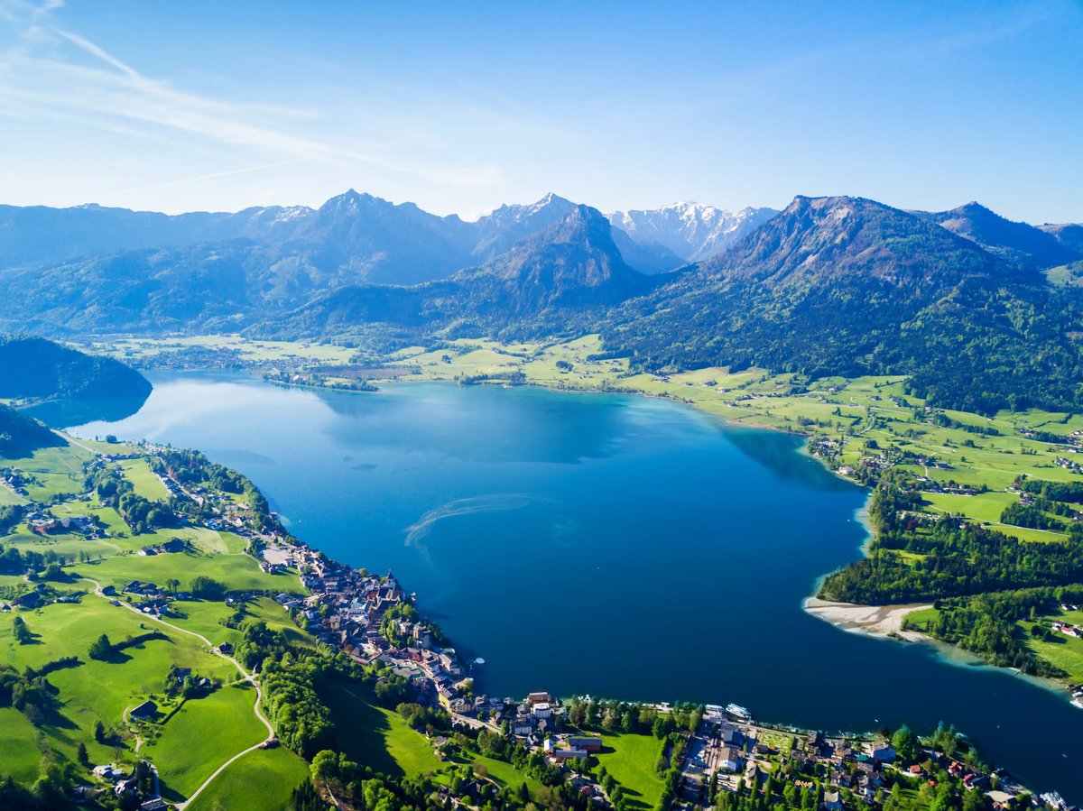 Vue aérienne d’un lac avec village et montagnes alentours