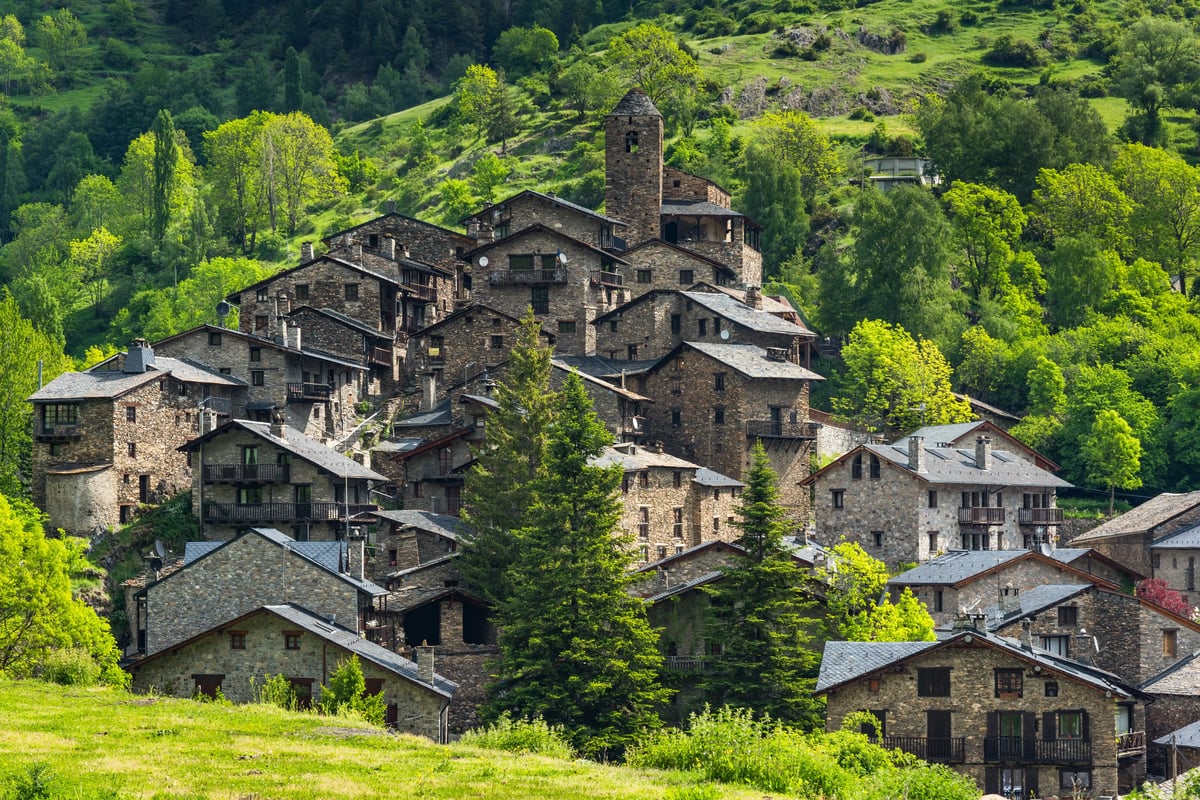 Typisches andorranisches Bergdorf mit Natursteinhäusern in grüner Hanglage