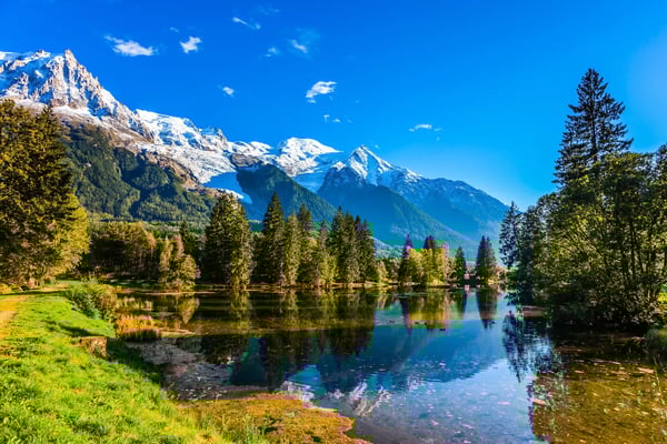 Alpenlandschaft bei Chamonix mit schneebedeckten Bergen, grünen Wäldern und ruhigem See mit Spiegelung