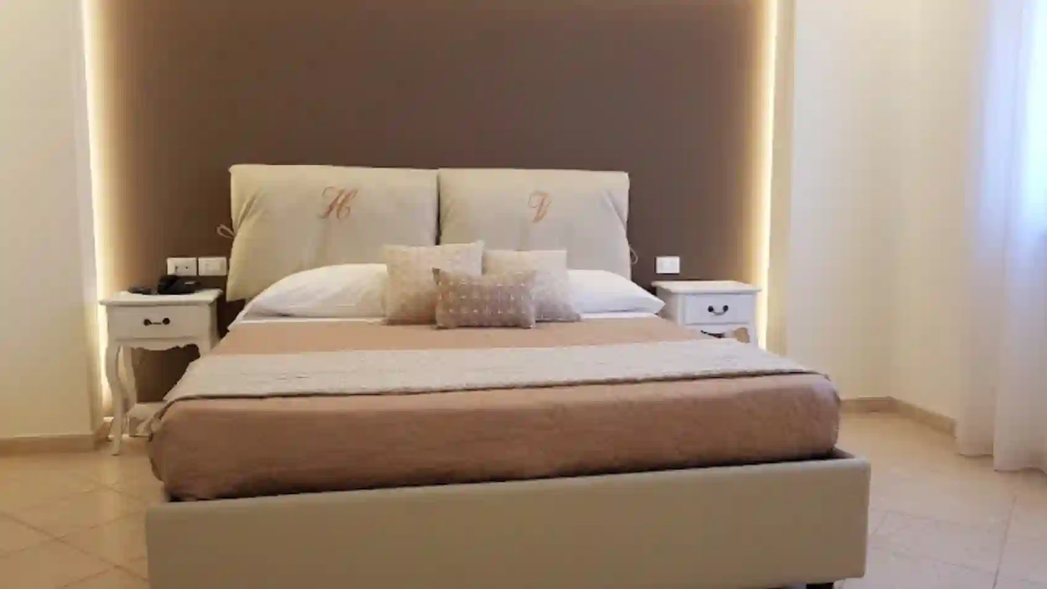 Modern eingerichtetes Hotelzimmer mit Doppelbett, Nachttischen und indirekter Beleuchtung in neutralen Farben