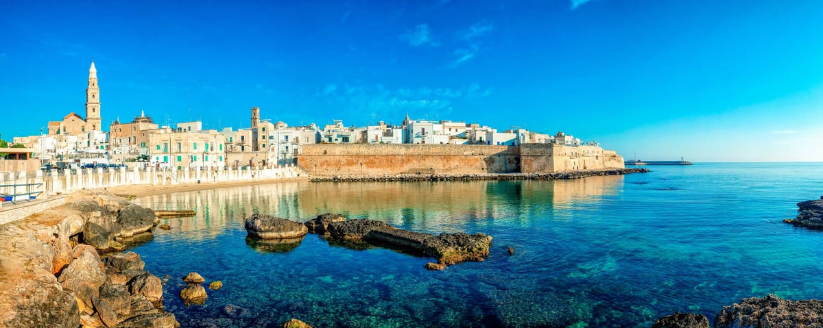 Altstadt von Monopoli mit Stadtmauer, Häusern und klarem Meer an der Adriaküste