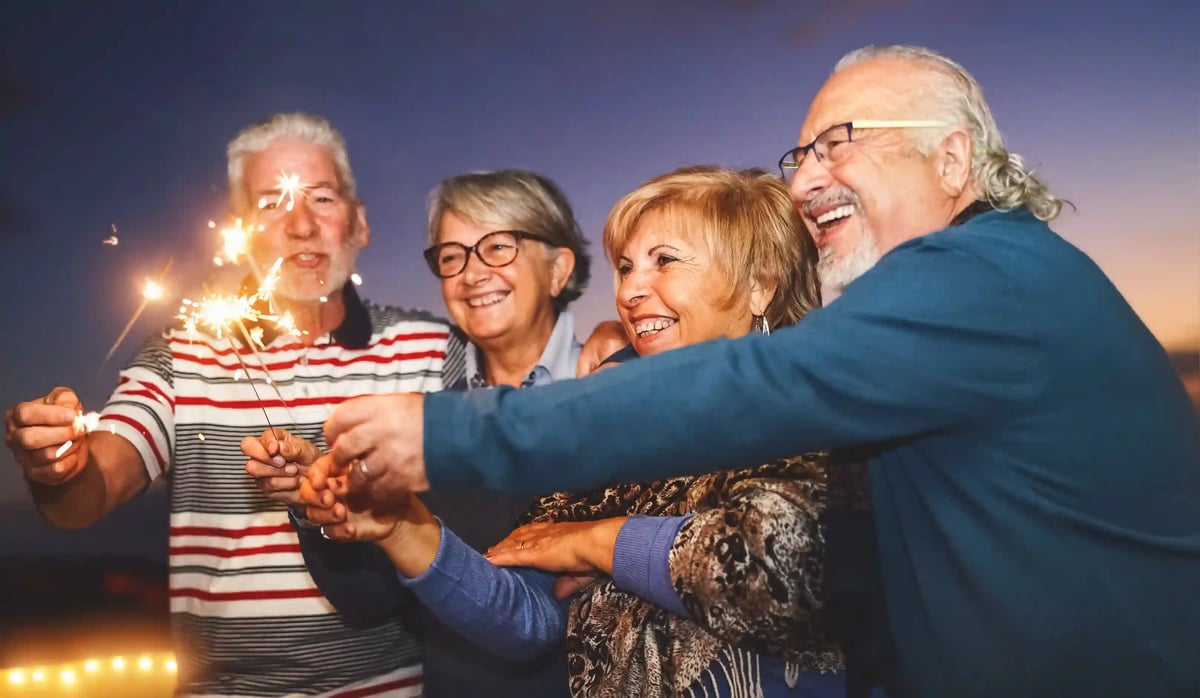 Fröhliche Gruppe von älteren Menschen hält Wunderkerzen und feiert gemeinsam im Freien