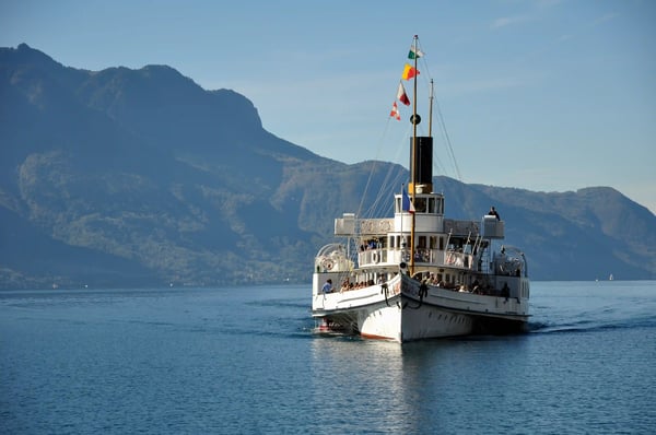 Passagierschiff fährt über den Genfersee mit Bergen im Hintergrund bei klarem Wetter