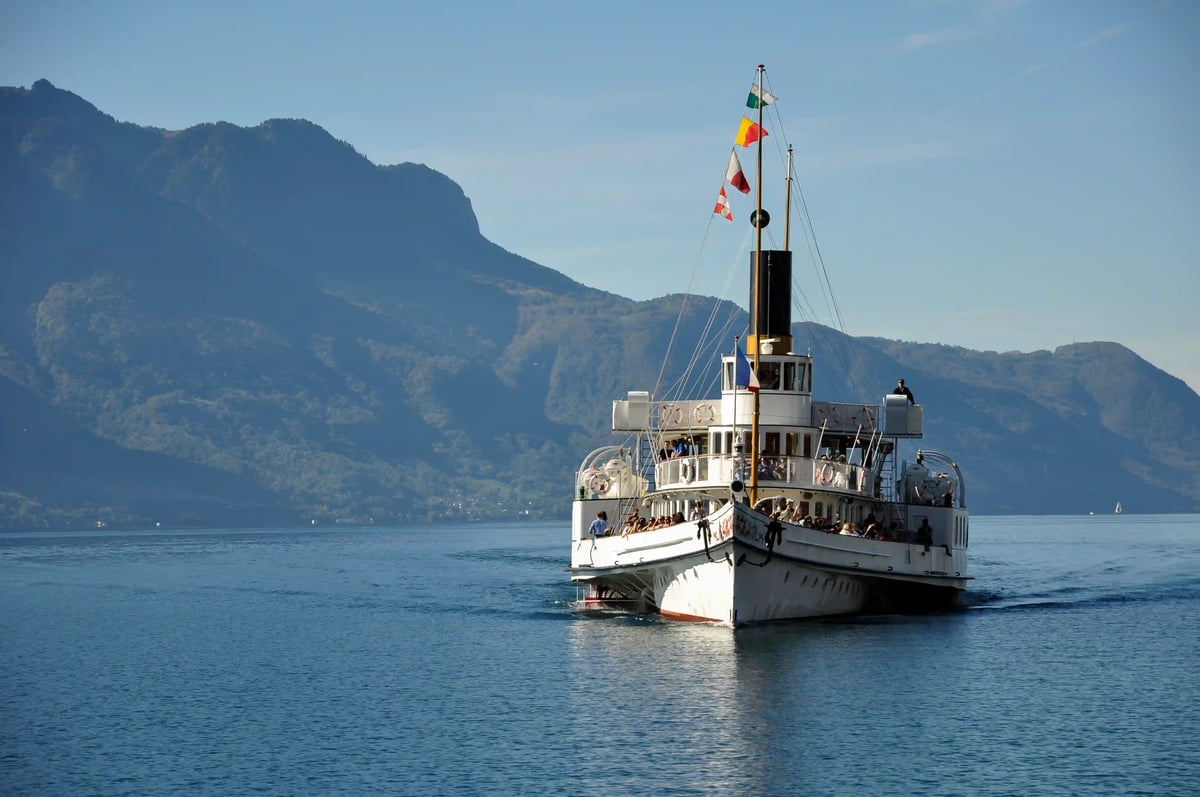 Passagierschiff fährt über den Genfersee mit Bergen im Hintergrund bei klarem Wetter