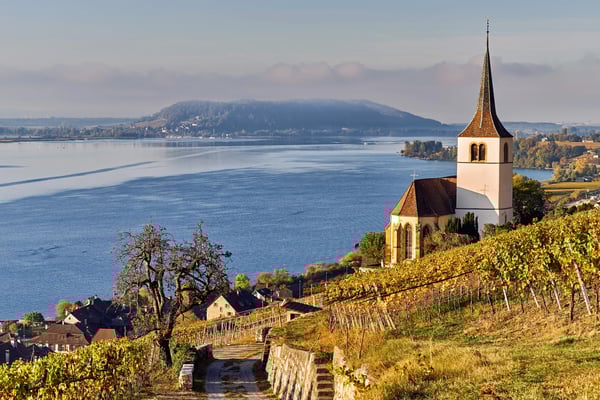 Kirche oberhalb von Weinbergen bei Ligerz mit Blick auf den Bielersee, sanfte Hügel und herbstliche Reben prägen die Landschaft