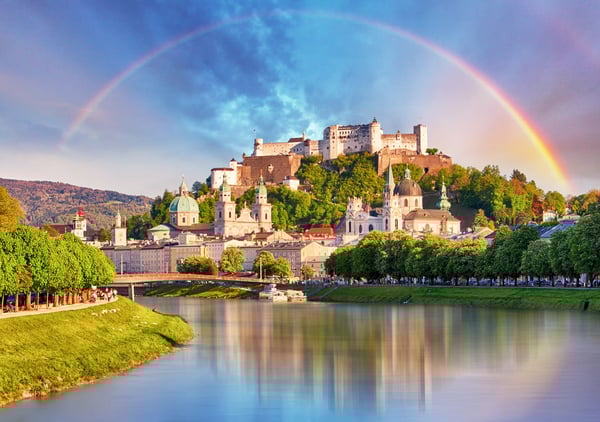 Festung Hohensalzburg über der Altstadt von Salzburg mit Regenbogen und Spiegelung im Fluss