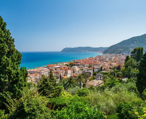 Blick auf die Küstenstadt Alassio mit roten Dächern, Palmen und türkisblauem Meer
