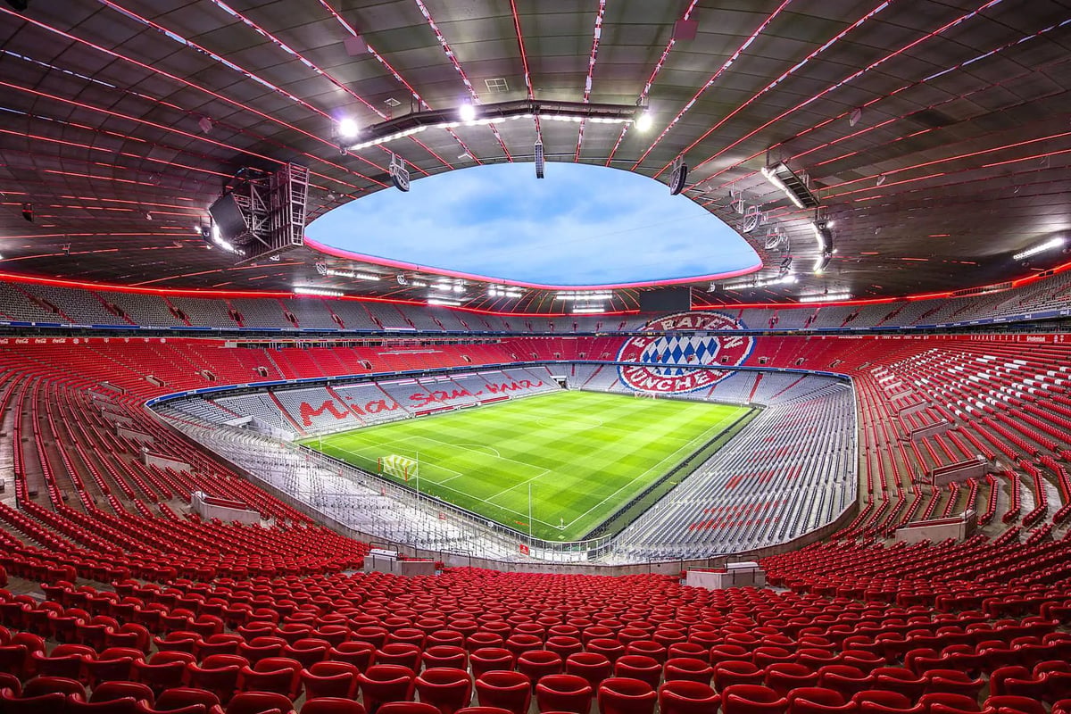 Innenansicht der Allianz Arena mit Spielfeld und roten Tribünen.