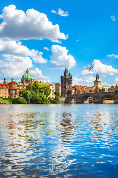 Blick auf die Prager Altstadt entlang der Moldau mit Bruecke, Tuerme und Spiegelungen im Wasser