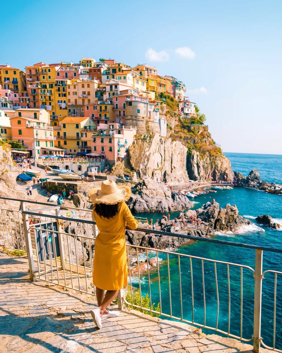 Person blickt von einem Aussichtspunkt auf die bunten Häuser der Cinque Terre und das türkisfarbene Meer