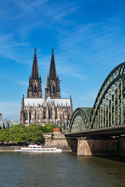 Blick auf den Kölner Dom mit seinen zwei Türmen neben der Hohenzollernbrücke am Rhein bei klarem Himmel