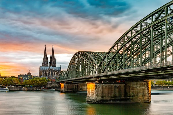Kölner Dom im Hintergrund der Hohenzollernbrücke bei Sonnenuntergang mit Spiegelungen im Rhein