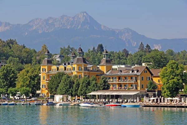 Blick auf Velden am Wörthersee mit Seeufer, Booten und Alpen im Hintergrund