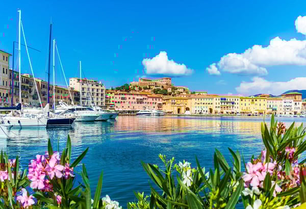 Hafen von Portoferraio auf der Insel Elba mit Booten, pastellfarbenen Häusern und Altstadt am Ufer