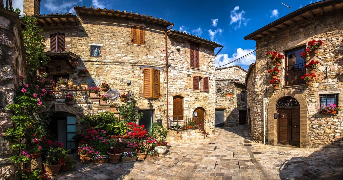 Maisons historiques en pierre avec volets et fleurs bordant une ruelle calme de la vieille ville de Pitigliano