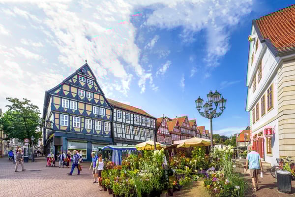 Historischer Marktplatz in Celle mit farbenfrohen Fachwerkhäusern, Blumenständen und Menschen beim Bummeln