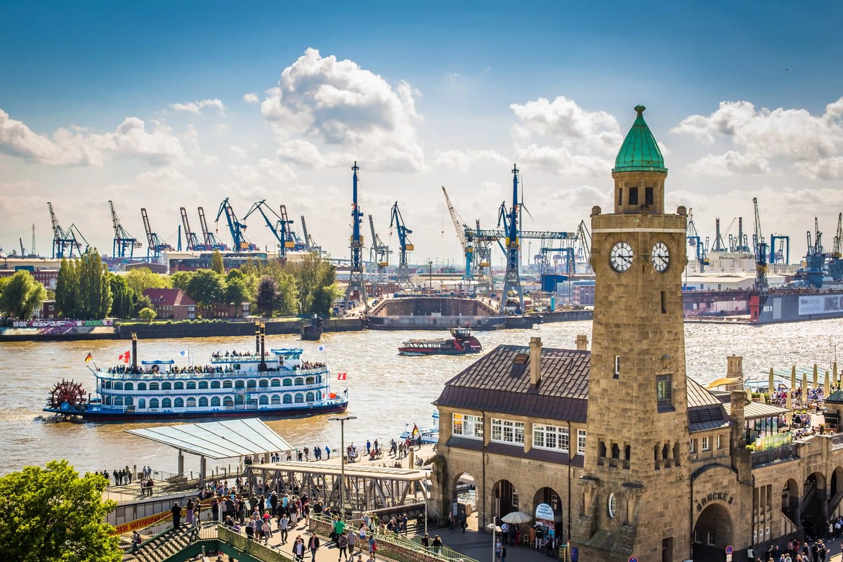 Blick auf den Hamburger Hafen mit Landungsbruecken, Uhrturm, Ausflugsschiff auf der Elbe und Hafenkranen im Hintergrund