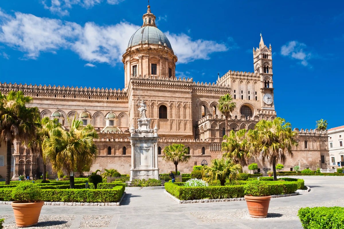 Cathédrale de Palerme avec palmiers, fontaine et place entretenue sous un ciel dégagé