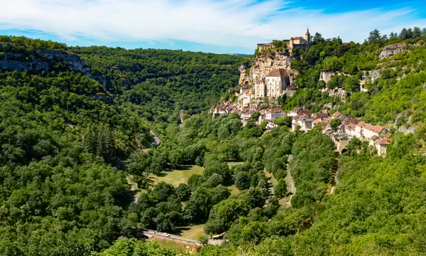 Felsdorf Rocamadour mit dicht stehenden Häusern und Heiligtümern, die sich terrassenförmig an eine steile Felswand schmiegen.