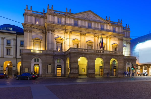 Beleuchtete Fassade des Teatro alla Scala in Mailand am Abend mit Arkaden und Vorplatz