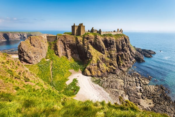 Ruinen von Dunnottar Castle auf steiler Klippe über dem Meer bei klarem Himmel