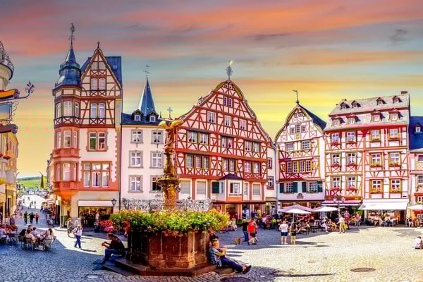 Historischer Marktplatz von Bernkastel-Kues mit bunten Fachwerkhäusern, Brunnen und Menschen auf dem Platz