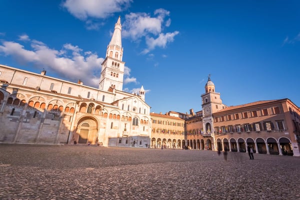 Historische Altstadt von Modena mit Dom, Glockenturm und gepflastertem Platz bei Sonnenschein