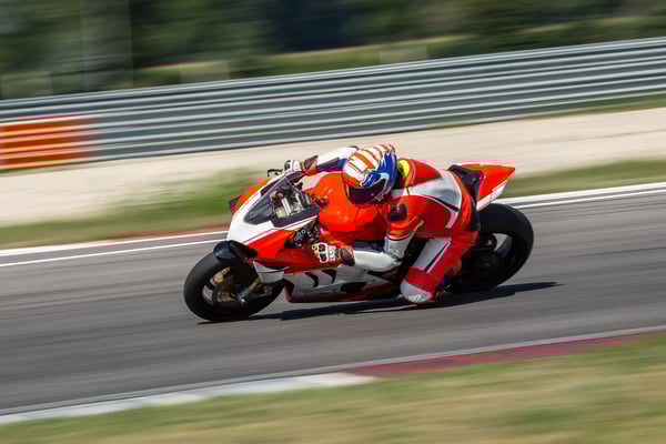Motorradrennfahrer in roter Schutzkleidung legt sich in einer schnellen Kurve auf einer Rennstrecke