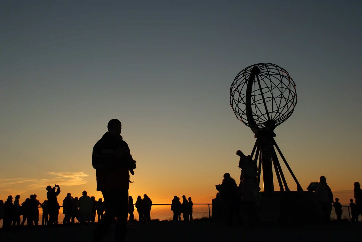 Nordkap mit Globusdenkmal bei Sonnenuntergang über einem Meer aus Wolken