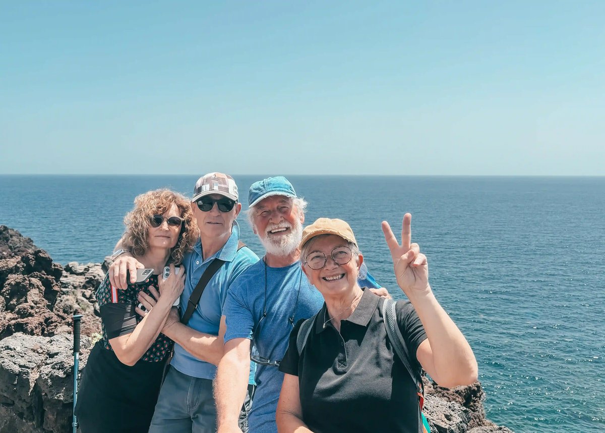 Reisegruppe am Nordkap mit Meer im Hintergrund, lächelnde Menschen posieren für ein Foto
