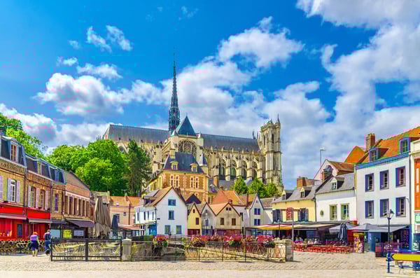 Blick auf bunte Häuser und die Kathedrale von Amiens bei blauem Himmel