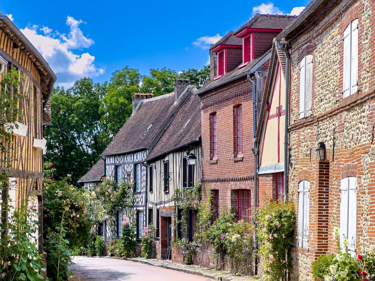 Rue étroite bordée de maisons à colombages et de roses en fleurs à Gerberoy