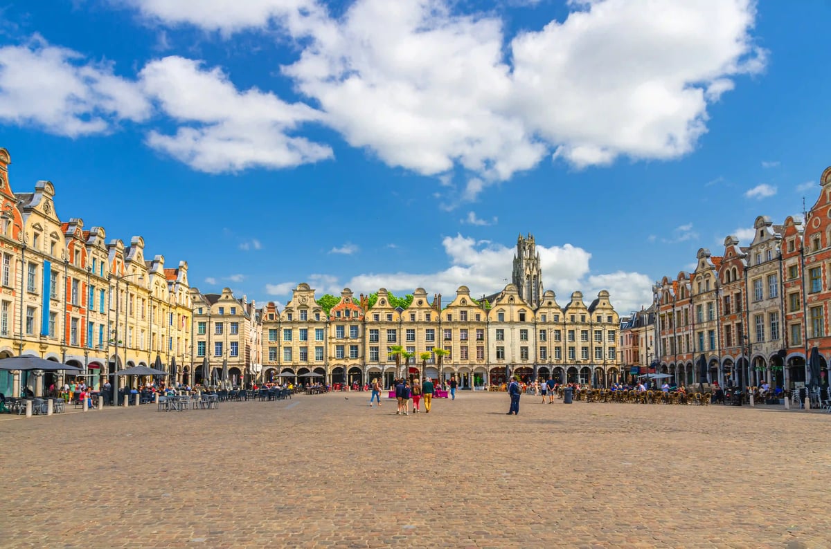 Grande place d Arras avec façades historiques et visiteurs sous un ciel ensoleillé