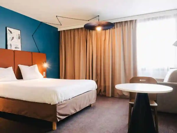 Modernes Hotelzimmer mit Doppelbett, Tisch und grossem Fenster mit Tageslicht