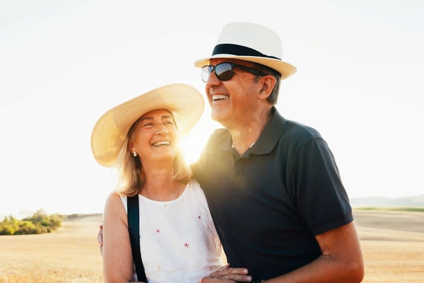 Älteres Paar lächelnd am Strand bei warmem Sonnenlicht