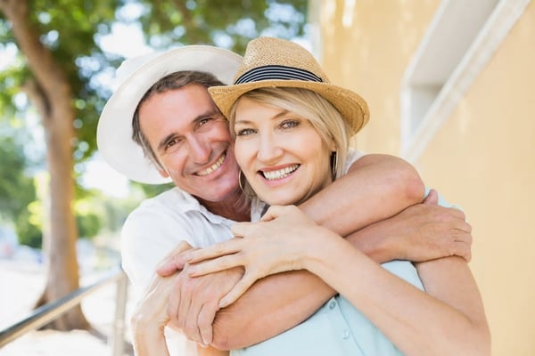 Lächelndes Paar umarmt sich entspannt im Urlaub im Freien bei sonnigem Licht