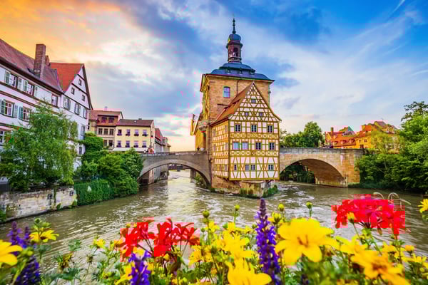 Historisches Rathaus mit Fachwerk über einem Fluss und Steinbrücke bei Abendlicht