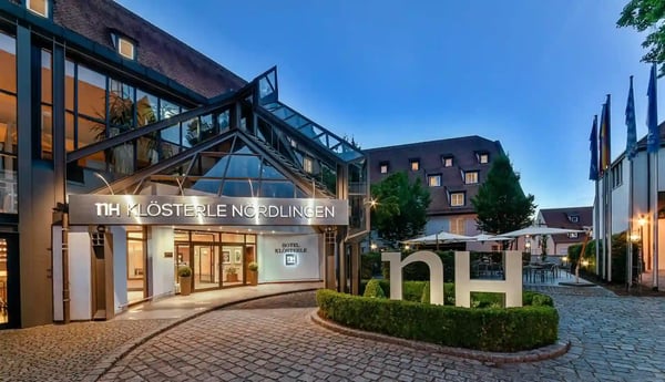 Eingangsbereich des elaya Hotels Nördlingen mit Glasdach, beleuchtetem Schriftzug und Innenhof am Abend