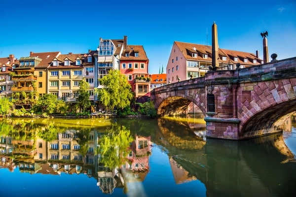 Steinerne Brücke in Nürnberg mit Fachwerkhäusern, Spiegelung im Fluss und klarem Himmel
